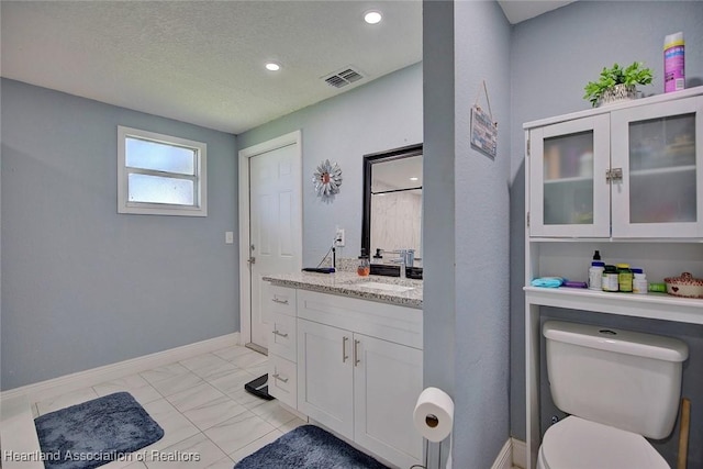 bathroom featuring toilet, tile patterned flooring, vanity, and a textured ceiling