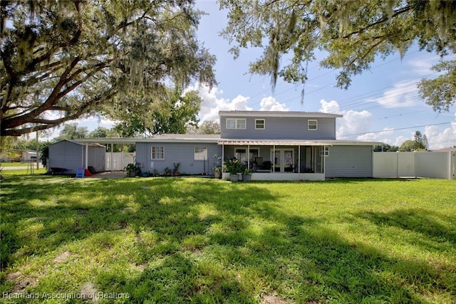 back of property with a yard, a storage unit, and a sunroom