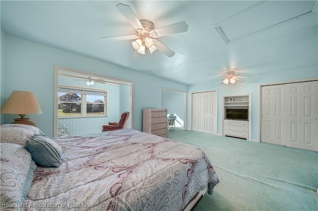 bedroom with ceiling fan, carpet floors, and two closets