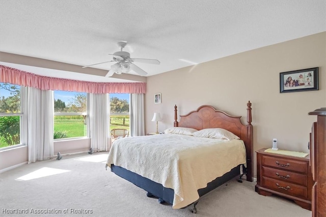 carpeted bedroom featuring ceiling fan and a textured ceiling