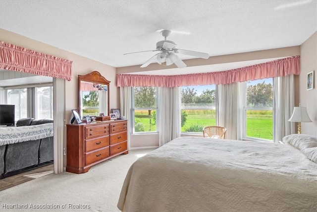 bedroom featuring a textured ceiling, ceiling fan, and light carpet