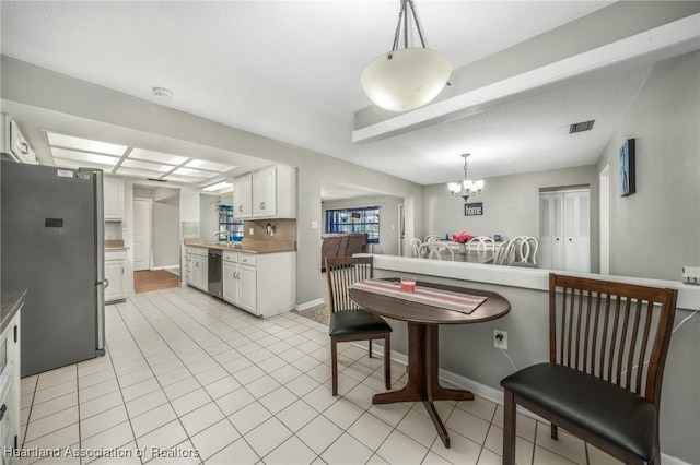 kitchen with visible vents, white cabinets, appliances with stainless steel finishes, hanging light fixtures, and an inviting chandelier