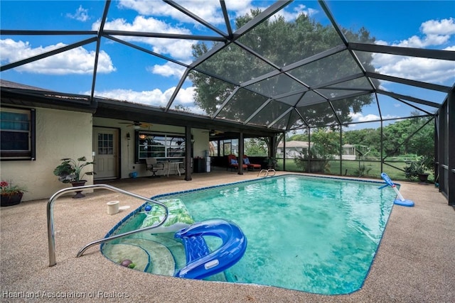 outdoor pool with a ceiling fan, glass enclosure, and a patio area