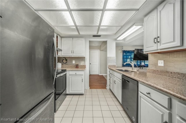 kitchen with light tile patterned floors, white cabinets, stainless steel appliances, light countertops, and a sink