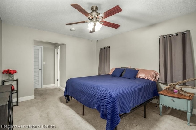 bedroom with a ceiling fan, light colored carpet, a textured ceiling, and baseboards