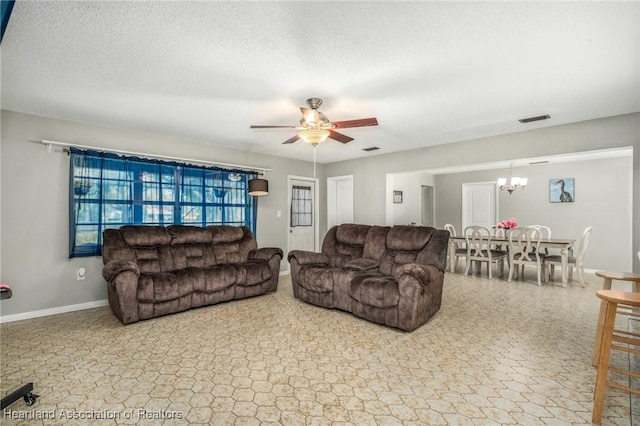 living room with baseboards, visible vents, a textured ceiling, and ceiling fan with notable chandelier