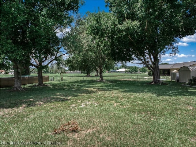 view of yard featuring a storage shed, fence, and an outdoor structure