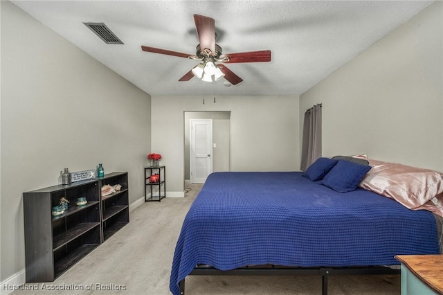 carpeted bedroom featuring baseboards, a textured ceiling, visible vents, and a ceiling fan