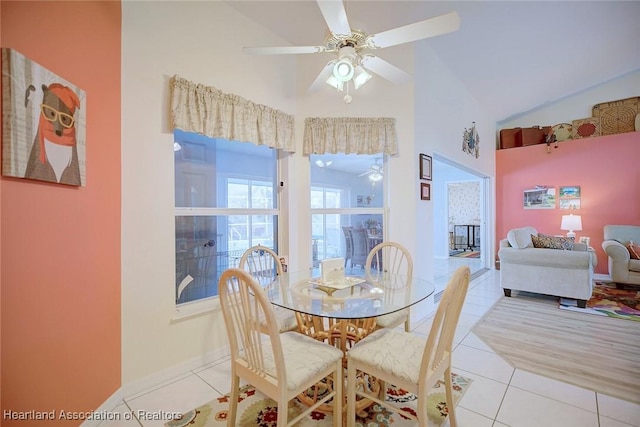 dining area with light tile patterned flooring, high vaulted ceiling, and ceiling fan