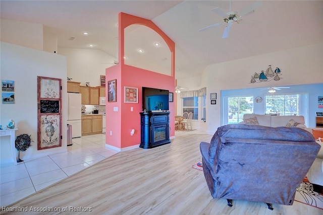 living room featuring ceiling fan, high vaulted ceiling, and light hardwood / wood-style flooring