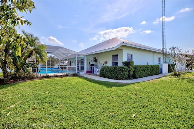 rear view of property featuring a yard and glass enclosure