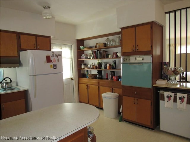kitchen featuring freestanding refrigerator, fridge, wall oven, and brown cabinets