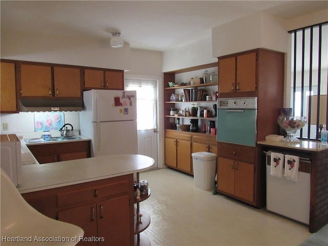 kitchen with freestanding refrigerator, wall oven, brown cabinets, and fridge