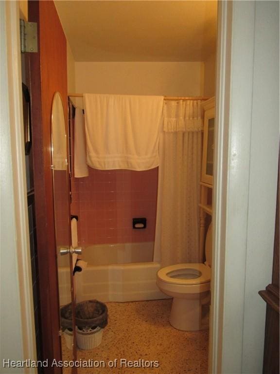 bathroom featuring toilet, speckled floor, and shower / tub combo