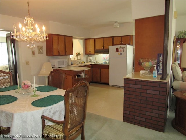 kitchen featuring brown cabinets, a notable chandelier, hanging light fixtures, white appliances, and light countertops