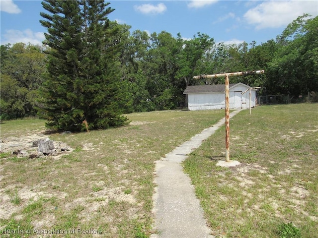 view of yard featuring a wooded view and an outbuilding