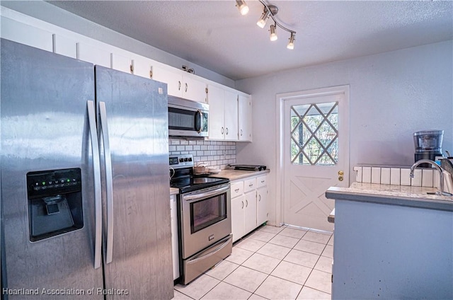 kitchen featuring light tile patterned floors, appliances with stainless steel finishes, white cabinets, and light countertops