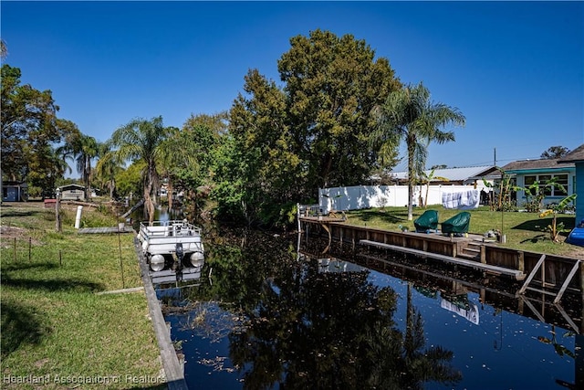view of dock with a yard, a water view, and fence