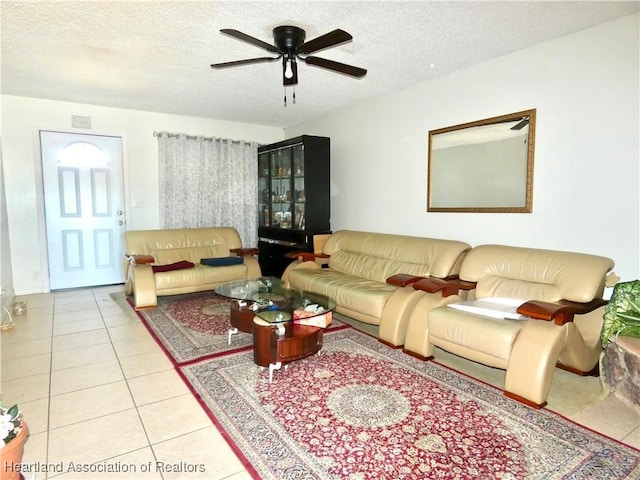 living area featuring tile patterned floors, a textured ceiling, and a ceiling fan
