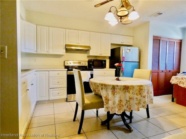 kitchen featuring a notable chandelier, light countertops, freestanding refrigerator, stainless steel electric stove, and black microwave