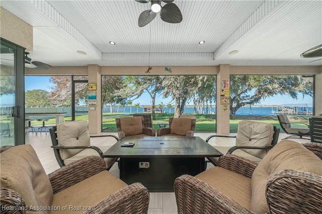 sunroom / solarium featuring a water view, ceiling fan, and a tray ceiling