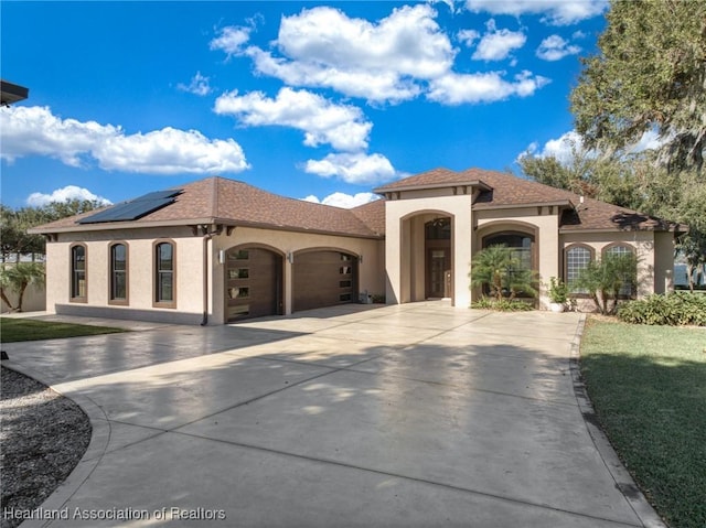 mediterranean / spanish house featuring a garage and solar panels