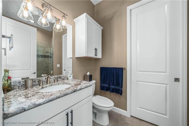 bathroom featuring tile patterned flooring, vanity, a tile shower, and toilet