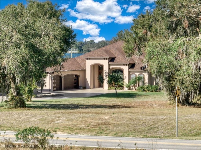 mediterranean / spanish-style house featuring a garage and a front lawn