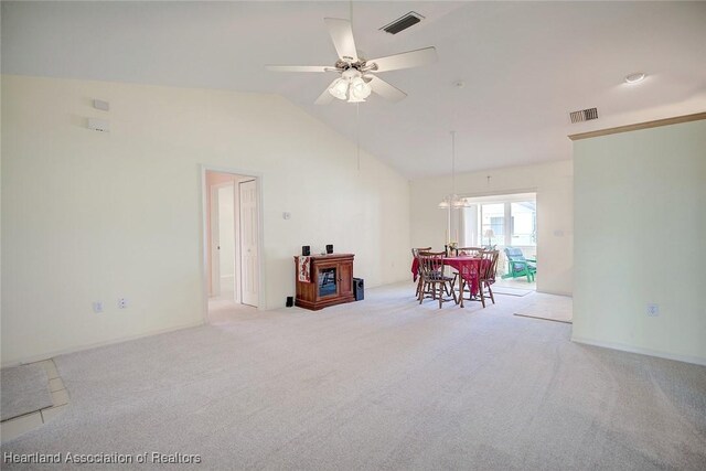 empty room featuring lofted ceiling, light carpet, and ceiling fan with notable chandelier