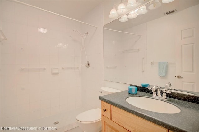 bathroom with tiled shower, vanity, and toilet