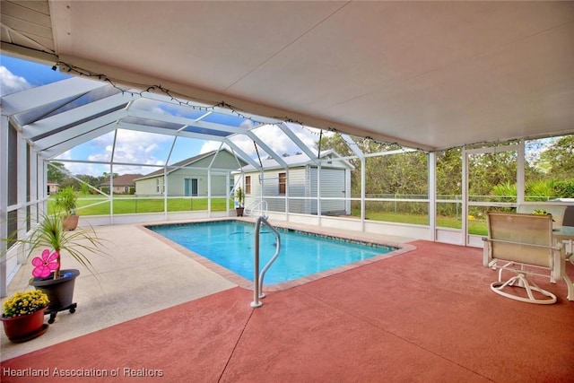 view of pool featuring a lawn, glass enclosure, a patio area, and a shed