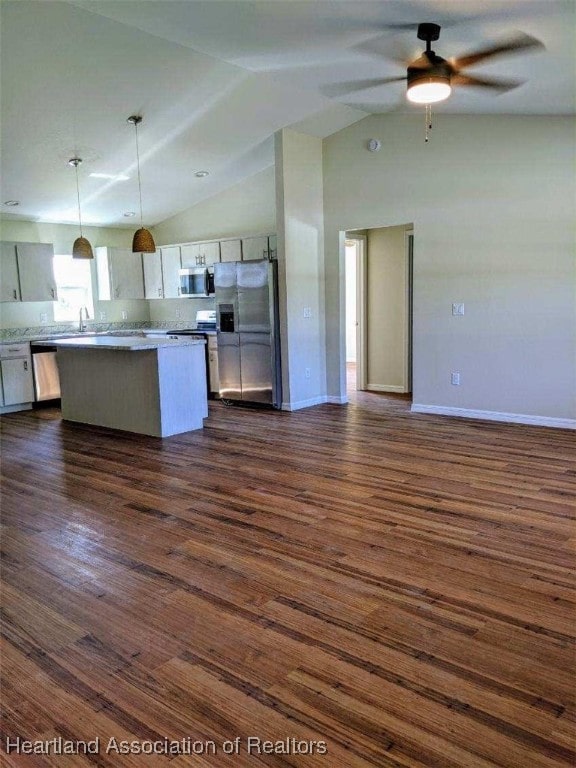 kitchen with dark wood finished floors, vaulted ceiling, appliances with stainless steel finishes, and baseboards