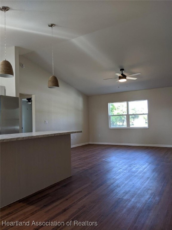 unfurnished living room featuring ceiling fan, lofted ceiling, and dark wood-type flooring