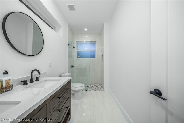 bathroom featuring vanity, a tile shower, and toilet