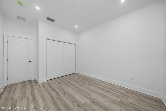 unfurnished bedroom with light wood-type flooring and a closet