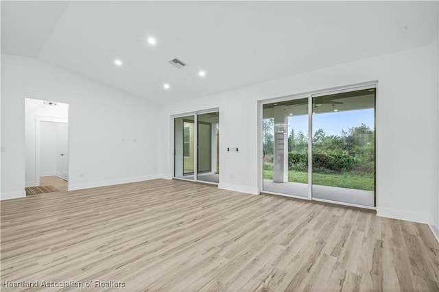 spare room featuring vaulted ceiling and light hardwood / wood-style flooring