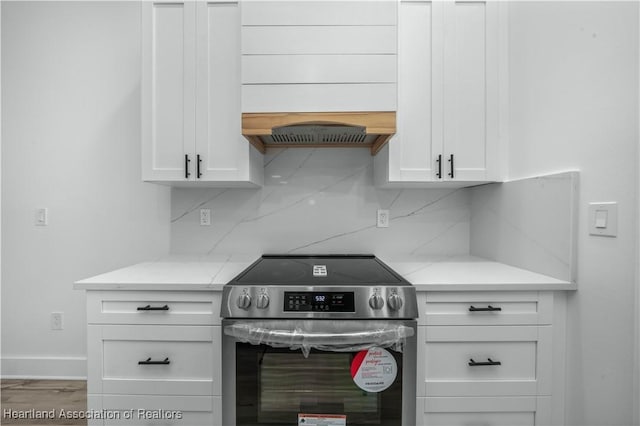 kitchen with white cabinetry, light stone countertops, and stainless steel electric range