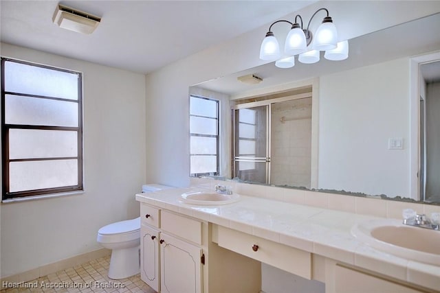 bathroom featuring a healthy amount of sunlight, vanity, toilet, and a shower with door