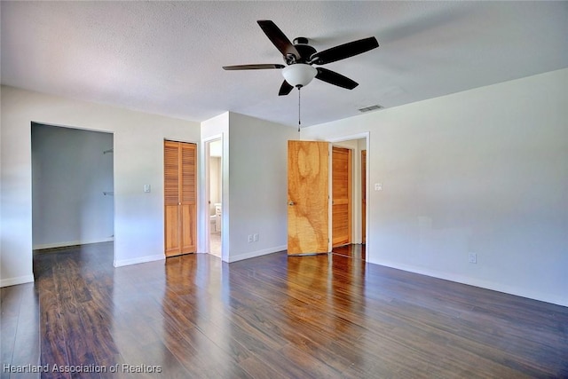 empty room featuring ceiling fan, a textured ceiling, and dark hardwood / wood-style flooring