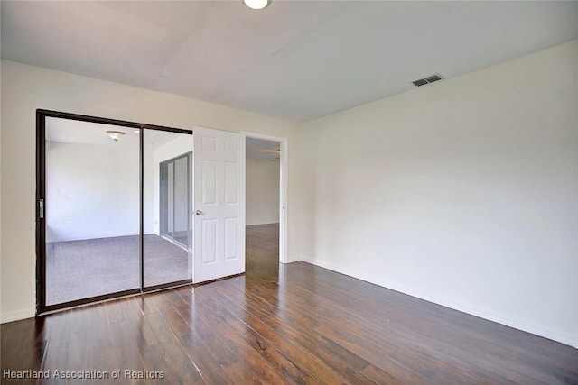 unfurnished bedroom featuring dark hardwood / wood-style floors and a closet