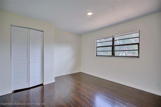 unfurnished bedroom featuring dark hardwood / wood-style flooring and a closet