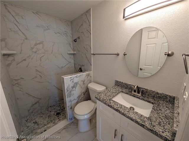 bathroom featuring tiled shower, vanity, and toilet