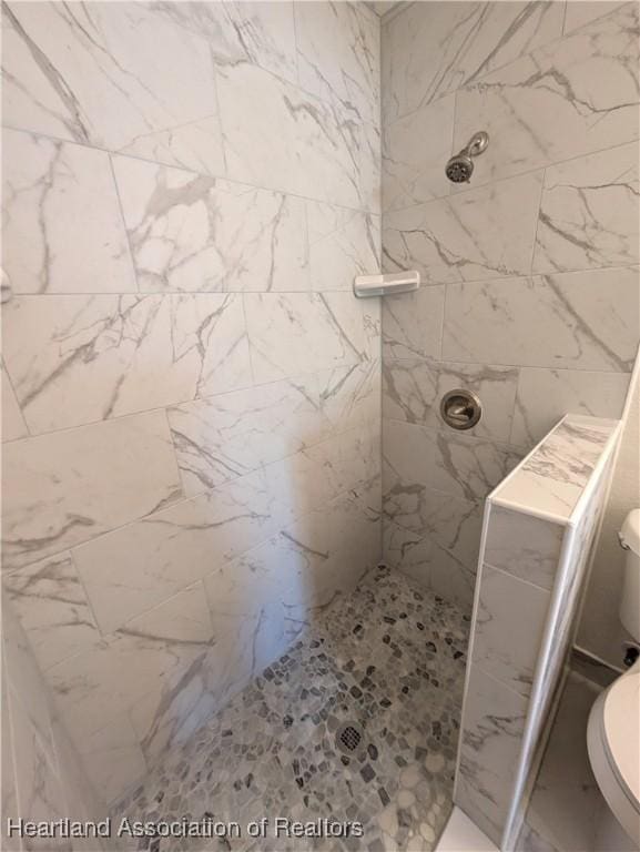 bathroom with tiled shower and toilet