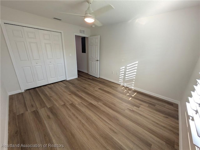 unfurnished bedroom with hardwood / wood-style flooring, ceiling fan, and a closet