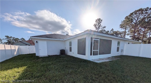 rear view of house featuring a lawn, central AC, and a sunroom