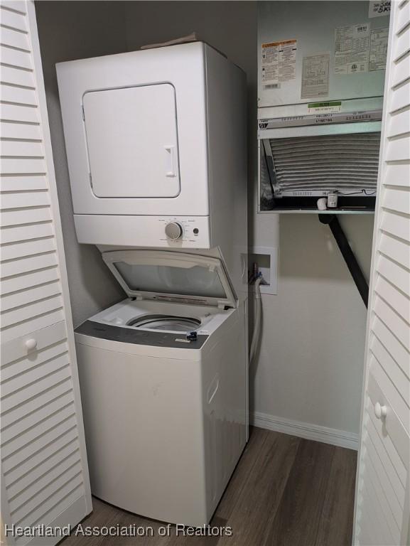 laundry room with dark wood-type flooring and stacked washer and clothes dryer