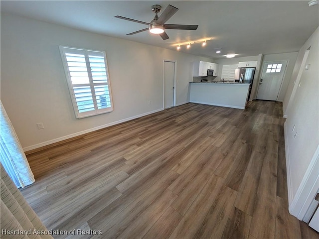 unfurnished living room with ceiling fan and dark hardwood / wood-style flooring