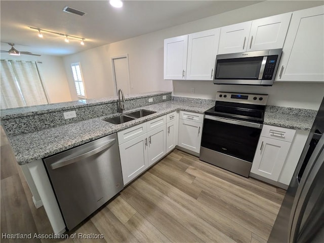 kitchen featuring kitchen peninsula, light hardwood / wood-style flooring, white cabinets, appliances with stainless steel finishes, and sink