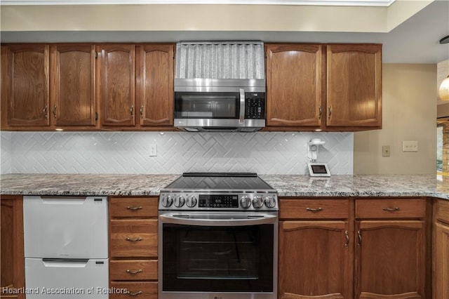 kitchen with tasteful backsplash, light stone counters, and appliances with stainless steel finishes