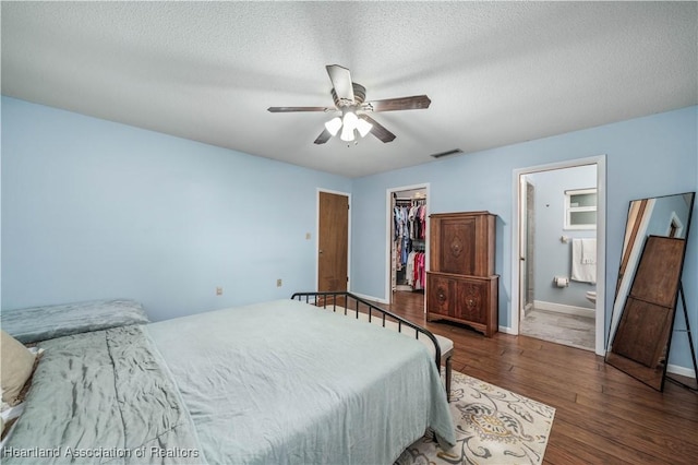 bedroom with ensuite bath, ceiling fan, a spacious closet, dark hardwood / wood-style flooring, and a closet